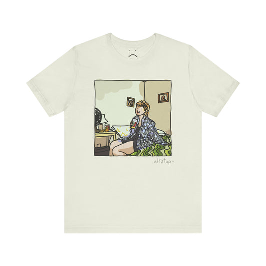 gorl with a cup on a bed deluxe tee